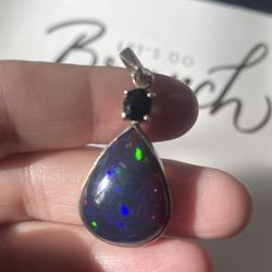 A silver Ethiopian opal pendant with an amethyst accent stone. 