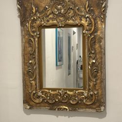 vintage or antique-style wall mirror with an ornate, gold-gilded 