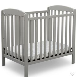 Delta Children Sprout Mini Crib in grey.