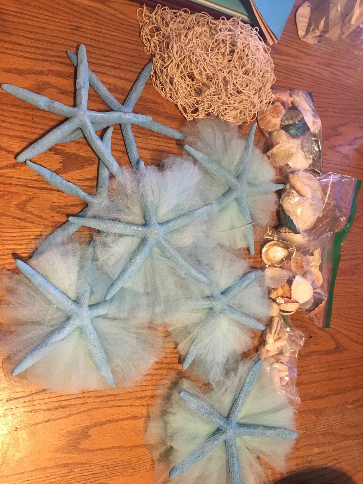 8 blue starfish and 4 small bags of seashells and one net