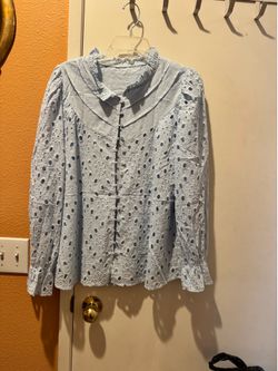 Light blue eyelet lined blouse with scalloped collar and decorative blue-covered buttons. Feminine long sleeves with subtle ruffle cuffs. Breathable c