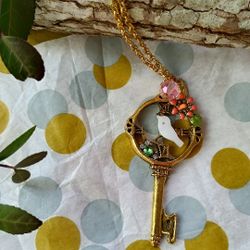 Adorable, long, gold tone skeleton key w carved bird and flower pendant necklace, gold tone chain