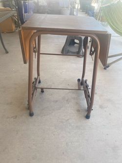vintage mid-century drop-leaf typewriter table with a brown metal frame and caster wheels
