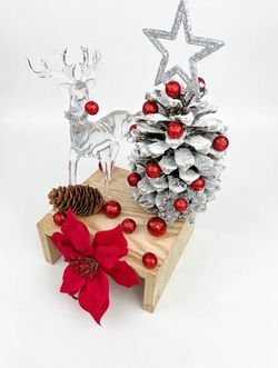 Handmade centerpiece featuring an acrylic reindeer and a small, snow-dusted pinecone tree adorned with cherries and a beautiful silver star.