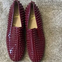 Christian Louboutin Roller-Boat slip-on sneaker in a dark red patent leather with tonal spikes. 