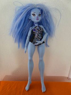 Blue Monster High Abbey Bominable doll has long hair with tinsel. This plastic fashion doll is from the G3 line and comes with a patterned swimsuit. I