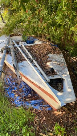 14 foot sailing hull with mast, tiller, center board - no sails.  Old trailer suited for sailboat .
