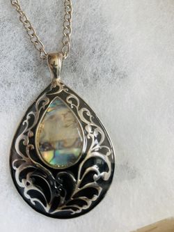 Multicolored iridescent Stone teardrop shape enclosed in a black and gold vine pendant necklace.