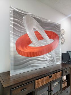 This piece is handcrafted by Nova Decoration Lighting in Huntington Park, California. It is a modern, abstract metal wall art piece featuring interloc