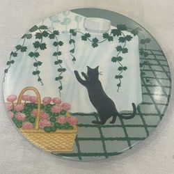 Italian melamine trivet with a black cat and floral basket design. 8”