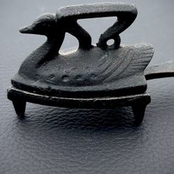 vintage miniature cast iron "sad iron" in the shape of a swan/duck accompanied by a matching trivet