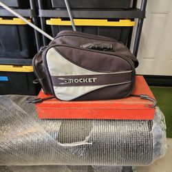 Joe rocket motorcycle or bicycle bag with bungie's underneath fitz, a helmet and maybe a jacket where the shoulder strap and arraign waterproof cover