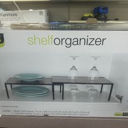 The Smart Design Expandable Kitchen Storage Shelf features a sleek black color and a modern SHELF style, making it a stylish addition to any kitchen. 