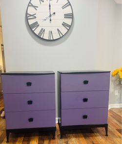 A pair of lavender three-drawer dressers with black handles.