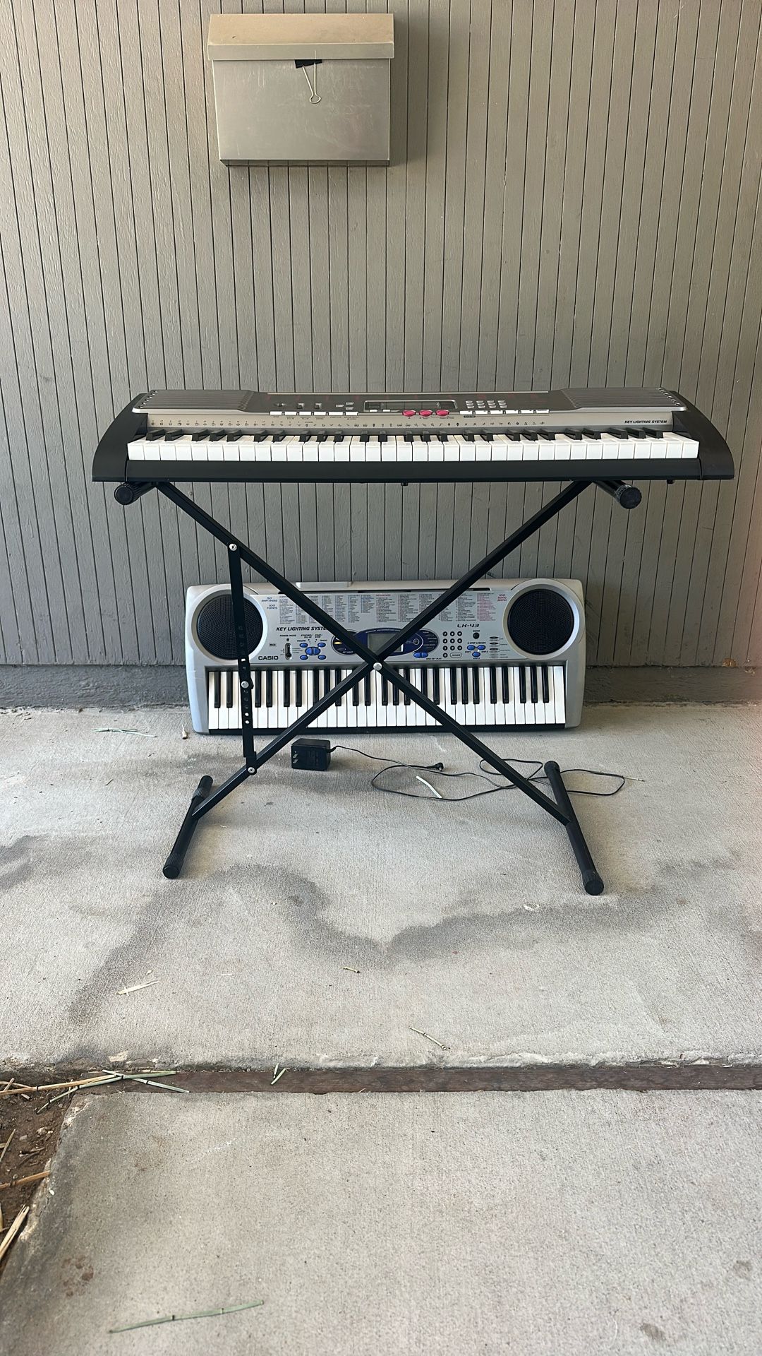 Two Casio Keyboards With One Cord And Stand