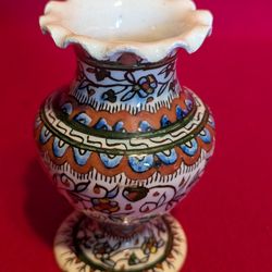 A vintage, hand-painted, ruffled-edge pottery vase with floral motifs.