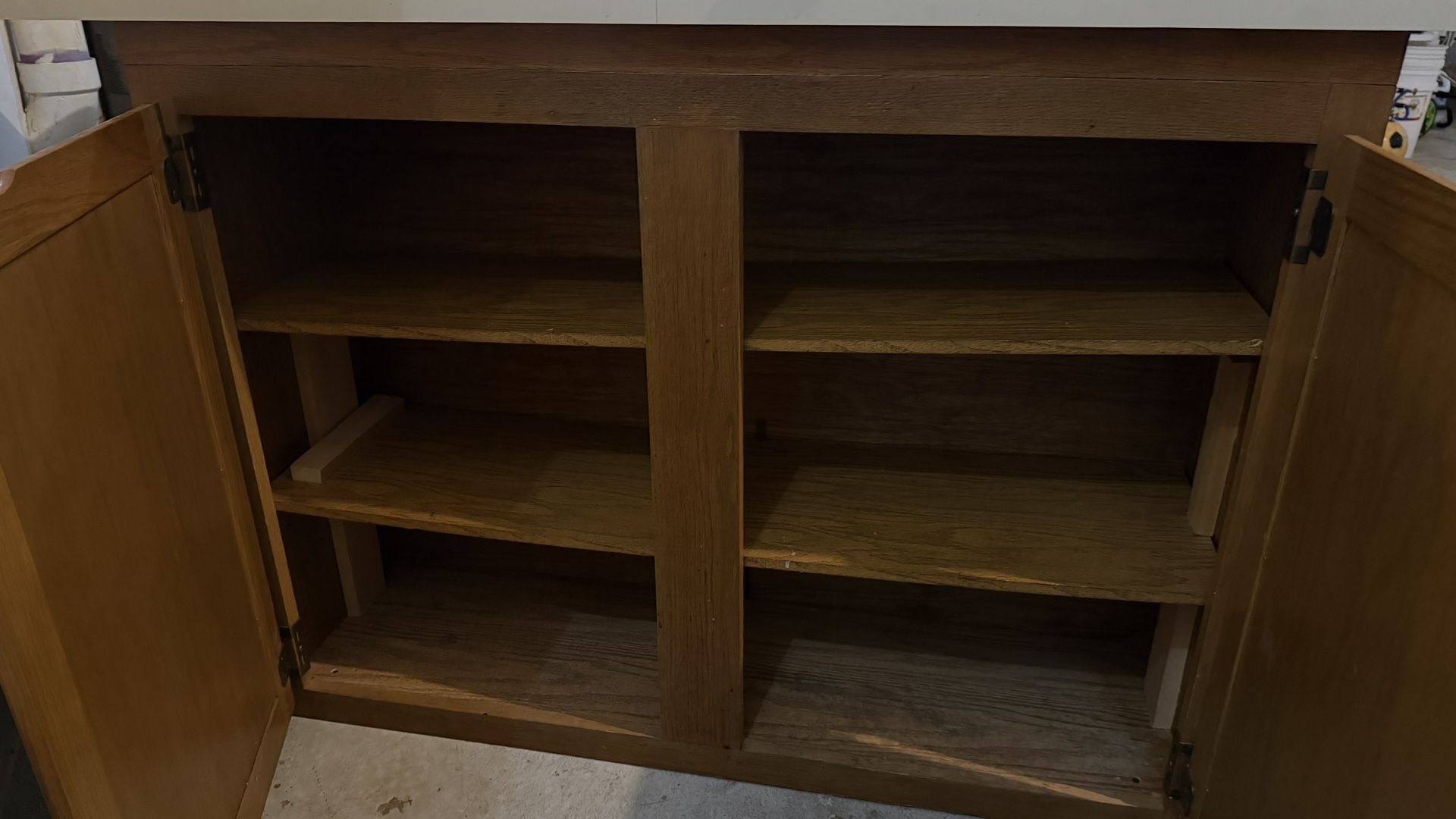 This appears to be a freestanding wood base storage cabinet with a laminate countertop, likely used in a utility area like a laundry room, garage, or