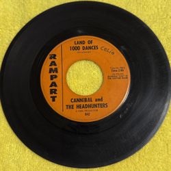 This item is a vintage 1965 7-inch vinyl record of "Land of 1000 Dances" by Cannibal and the Headhunters, released on the Rampart Records label. 