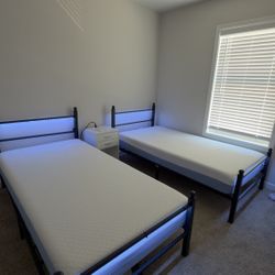 Two twin beds with mattresses and a dresser for sale.
