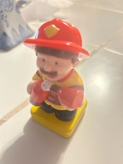 vintage plastic firefighter figure, resembling toddler-friendly chunky figures from brands like Mega Bloks or similar preschool playsets. It features 