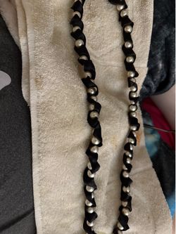 Very long necklace on ribbon with pearls all along length on necklace.