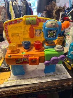 This is a Fisher-Price Laugh & Learn Learning Tool Bench, featuring colorful interactive shapes and a cheerful cartoon roller.