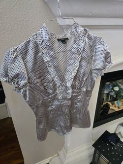 Feminine V-neck blouse with ruffle trim. Short puff sleeves with gathered detail. Flattering fitted waist and button front. Lightweight and versatile 