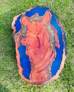 Carved wooden slab with horse details, live edge, and blue epoxy resin.