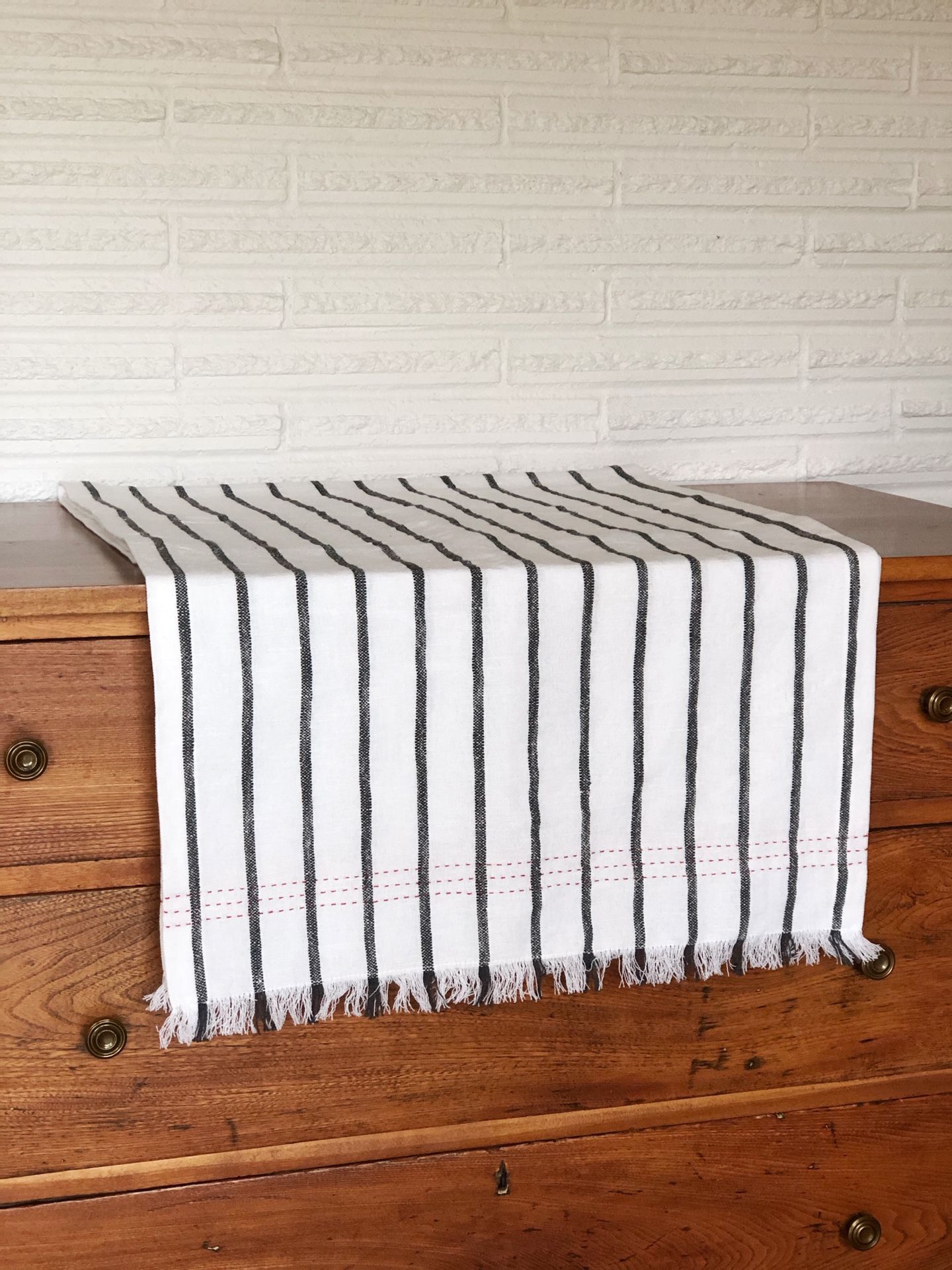 Brand new black and white striped table runner with red detailing on the end