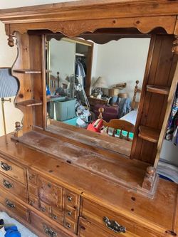 This rustic pine dresser features multiple drawers with ornate brass-colored hardware and carved decorative accents.