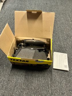 Open-box brake pad set in original Textar packaging. The box shows storage and handling wear. Includes the brake pads, pictured hardware, and instruct