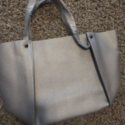 Neiman Marcus Silver Tote. Top Length 19", Bottom Length 11", Width 5", Height 12". Handle Length 6". Faux-leather.