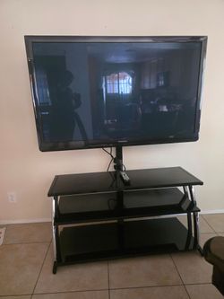 Black tempered glass TV stand with a 50inch Panasonic TV.