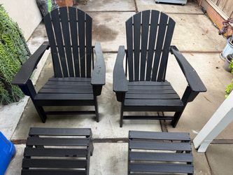 Set of two black Adirondack chairs with matching ottomans.