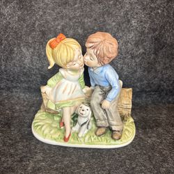 Little Boy Kissing Little Girl On Log With Puppy Dog Figurine