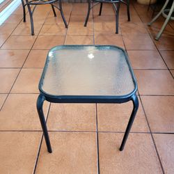 Black steel side table, glass top, from the Four Seasons Courtyard brand, specifically the Sunny Isles model. M. 16" x 16" x 18".