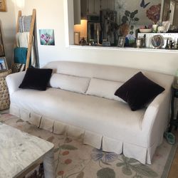 Cream Sofa With Pleated Accent And Two Purple Velvet Pillows