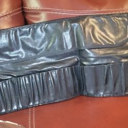 makeup brush case. These are black, typically made of leather or faux leather, and designed as a roll-up case with multiple slots for brushes and a pr