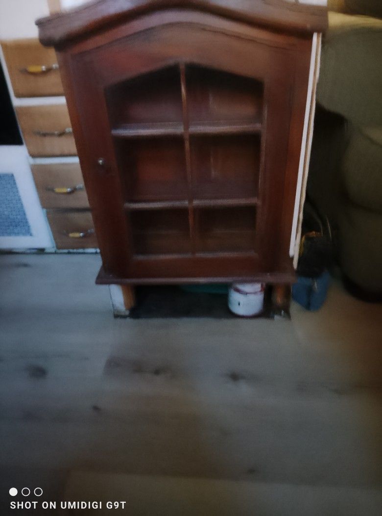 This is a vintage wooden wall-mounted display or curio cabinet with a glass door
