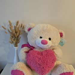 Valentine's teddy bear holding a heart-shaped pillow.