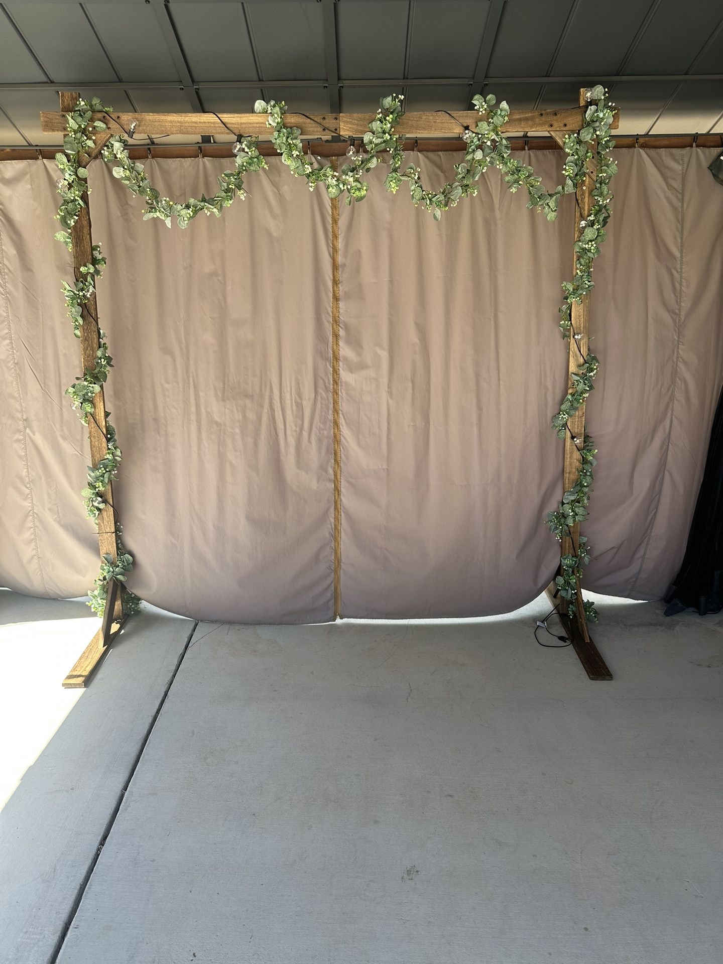 Wedding Arch Decorated With Lights And Green Garland