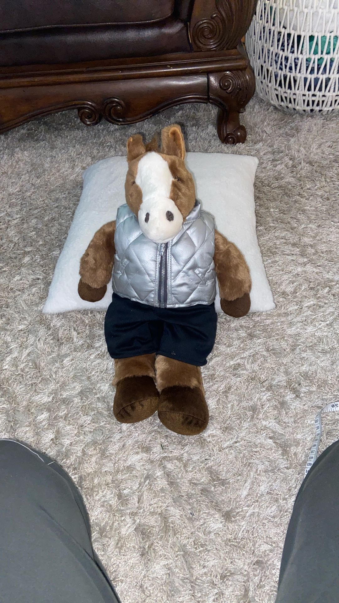 A plush sitting horse toy wearing a silver vest and black bottoms.18”