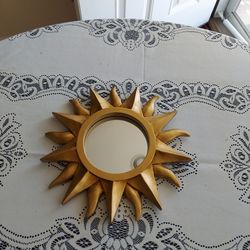 This is a 1980s round bohemian sunburst wall mirror featuring a carved wood frame with a gold finish