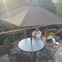 Round Glass Patio Table With Striped Umbrella And Matching Chairs