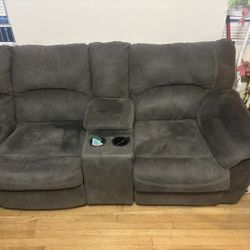 Signature Design by Ashley reclining sectional sofa,possibly the Tambo model, featuring a dark grey fabric upholstery. 