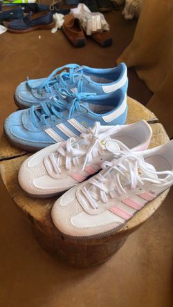 Two. Pairs of kids, samba  Adidas, one baby blue, one White with pink.