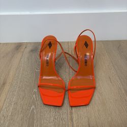 The Attico Ankle Strap Sandals in a neon orange color