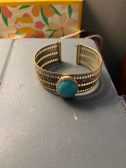 bohemian-style cutout cuff bracelet featuring a central oval turquoise cabochon stone.