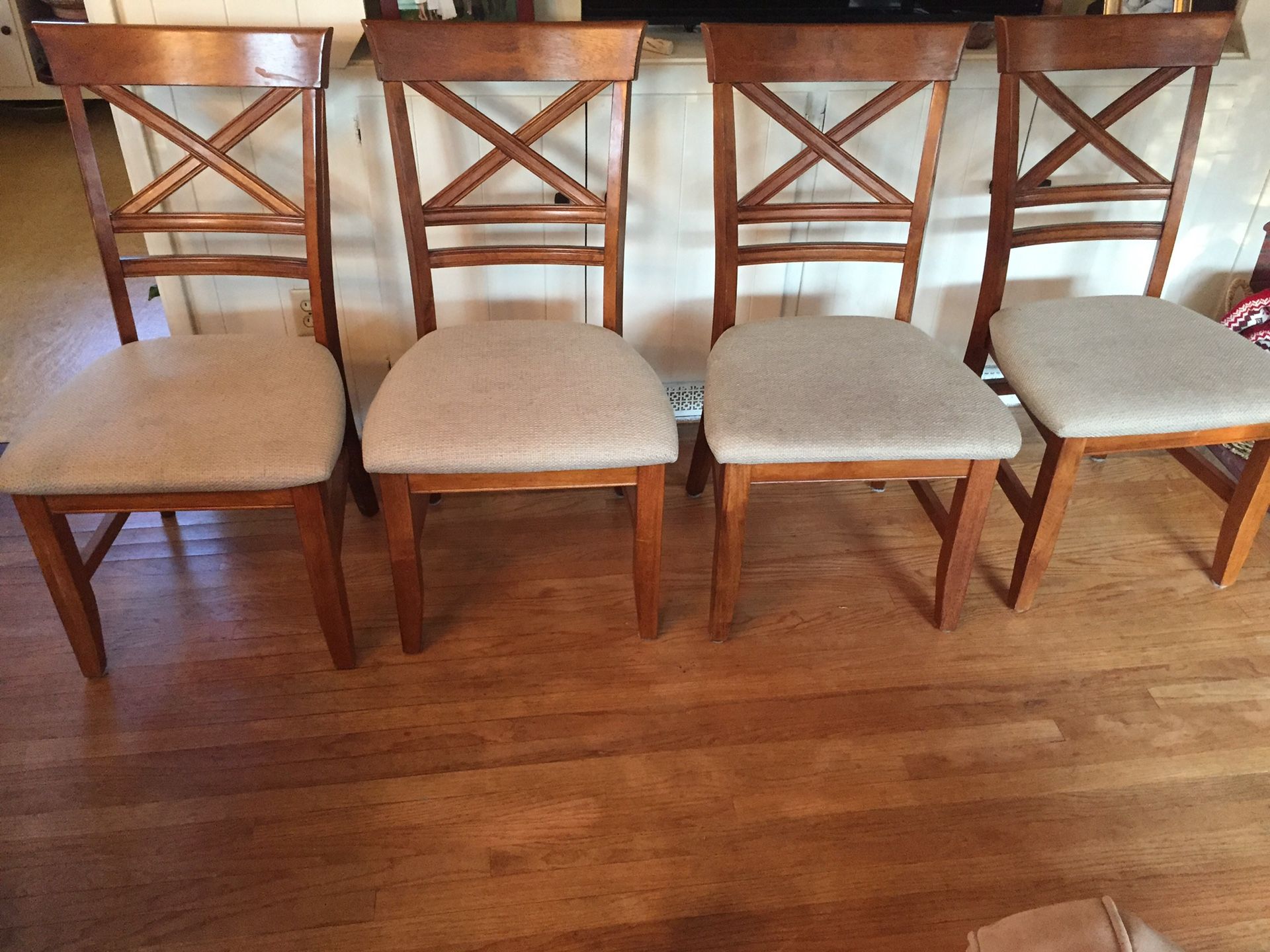 Oak dining room table with four padded chairs.
