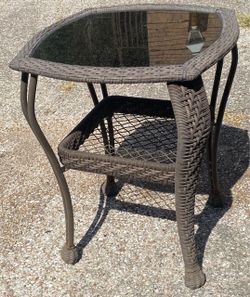 gray resin wicker outdoor side table with a tempered glass top and a lower storage